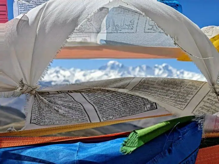 Bandeiras de oração ao vento, com os gigantes dos Himalaias no horizonte.
