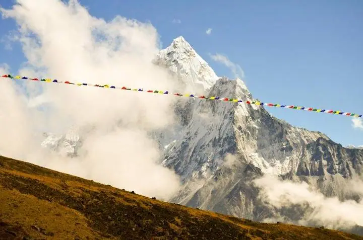 Bandeiras de oração ao vento diante do Ama Dablam, envolto em nuvens.