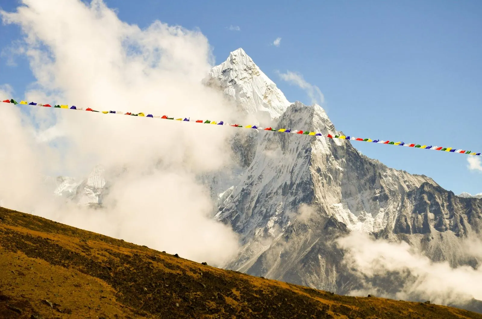 Bandeiras de oração ao vento diante do Ama Dablam, envolto em nuvens.