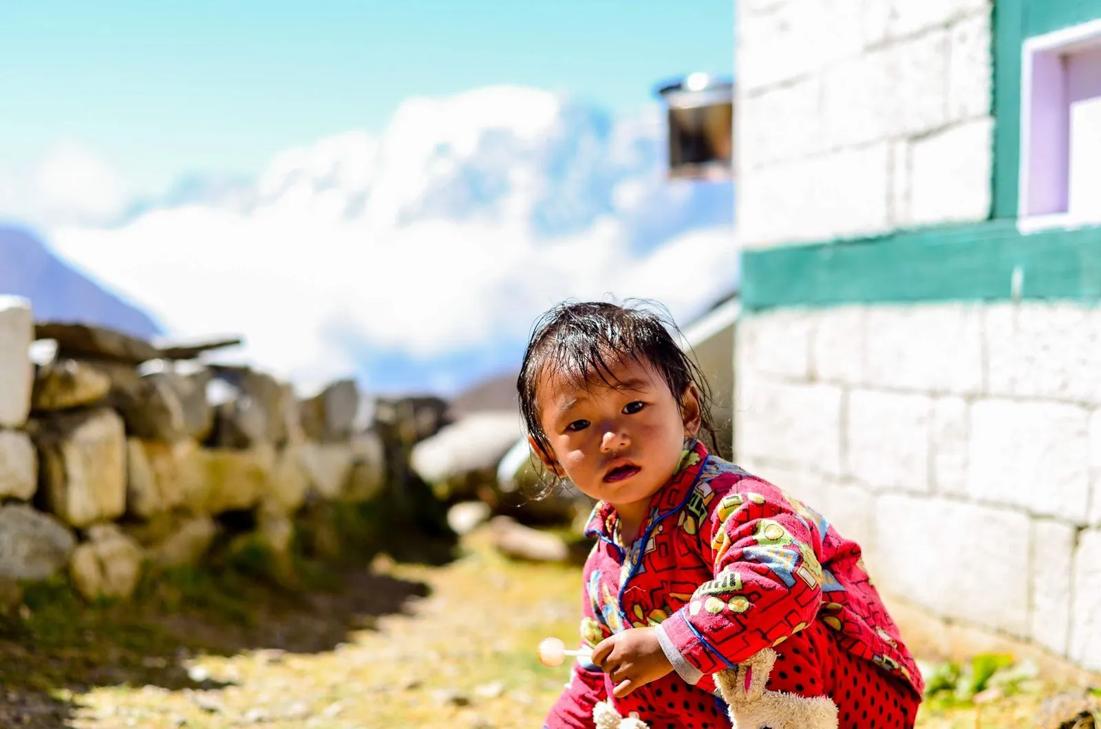 Uma criança numa aldeia do vale do Khumbu, junto a uma casa de pedra caiada.